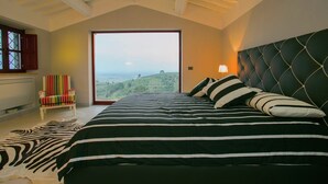 Une chambre avec un grand lit, un tapis à motifs zébrés, une chaise et une vue sur le paysage.