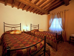 A bedroom with two beds, a wooden ceiling, and a window with curtains. - Belvilla by OYO Seccatoio (Cortona)