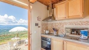 Una cucina con vista sulla campagna, una parete di fondo in mattoni, mobili in legno e un piano di lavoro in pietra.