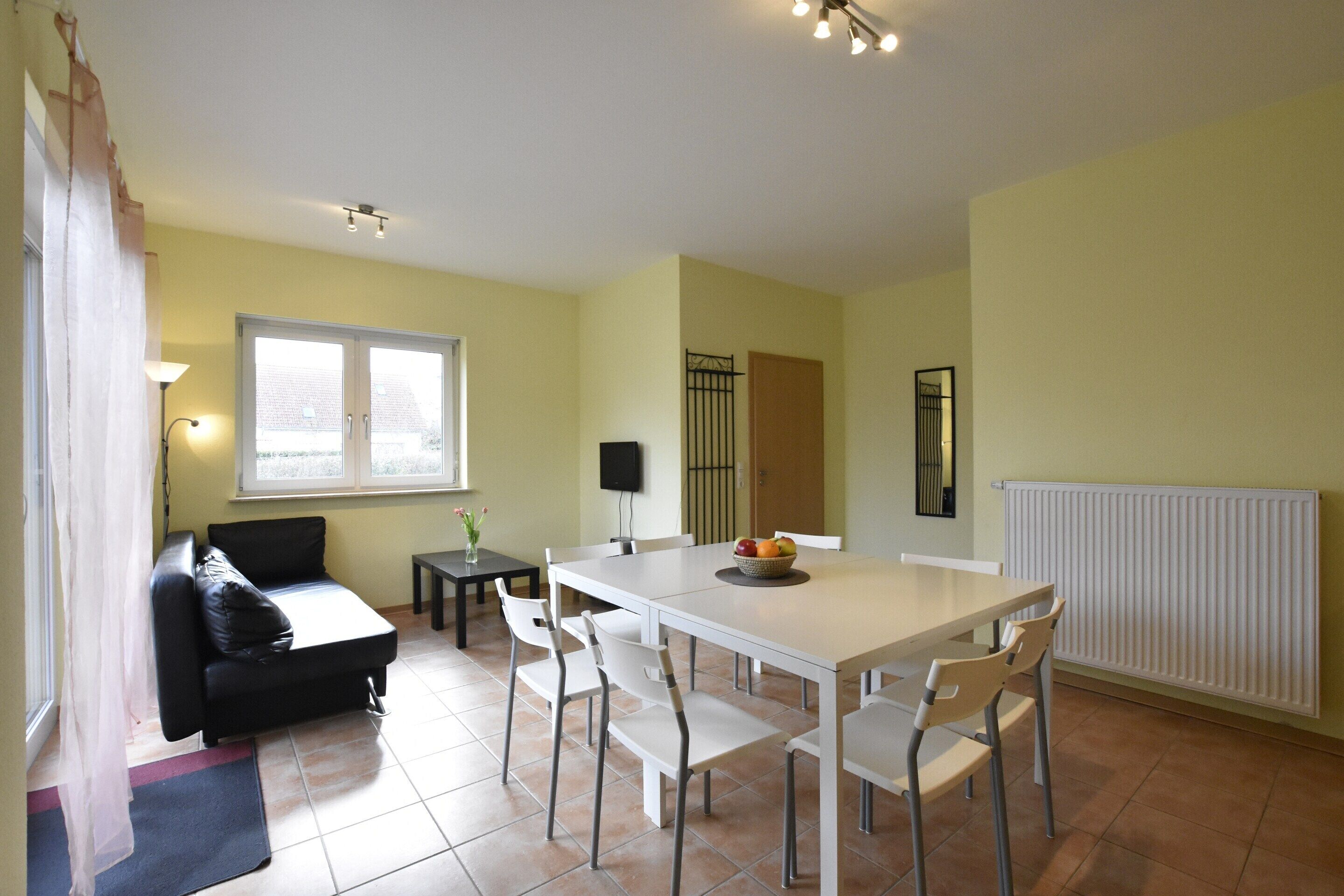 A dining area with a table, chairs, a sofa, and a window.