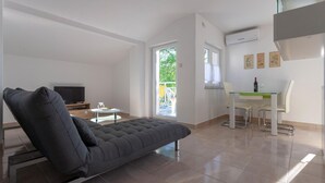 A modern living room with a sofa, a TV, a dining table with chairs, and a balcony with a view. - Apartment in Sveti Vid Near the Adriatic (Malinska-Dubasnica)