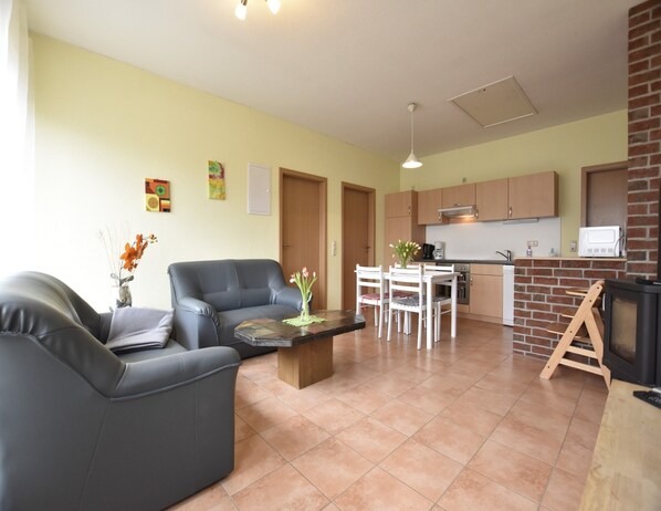 A living room with a sofa, a coffee table, and a dining table with chairs. There is a kitchen area with cabinets and a microwave. - Zierow Ferienhaus mit Sauna (Zierow)