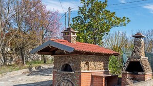 A stone and brick structure with a red-tiled roof, a wooden door, and a chimney. - Apartment in Cassinelle With Garden & BBQ (Cassinelle)