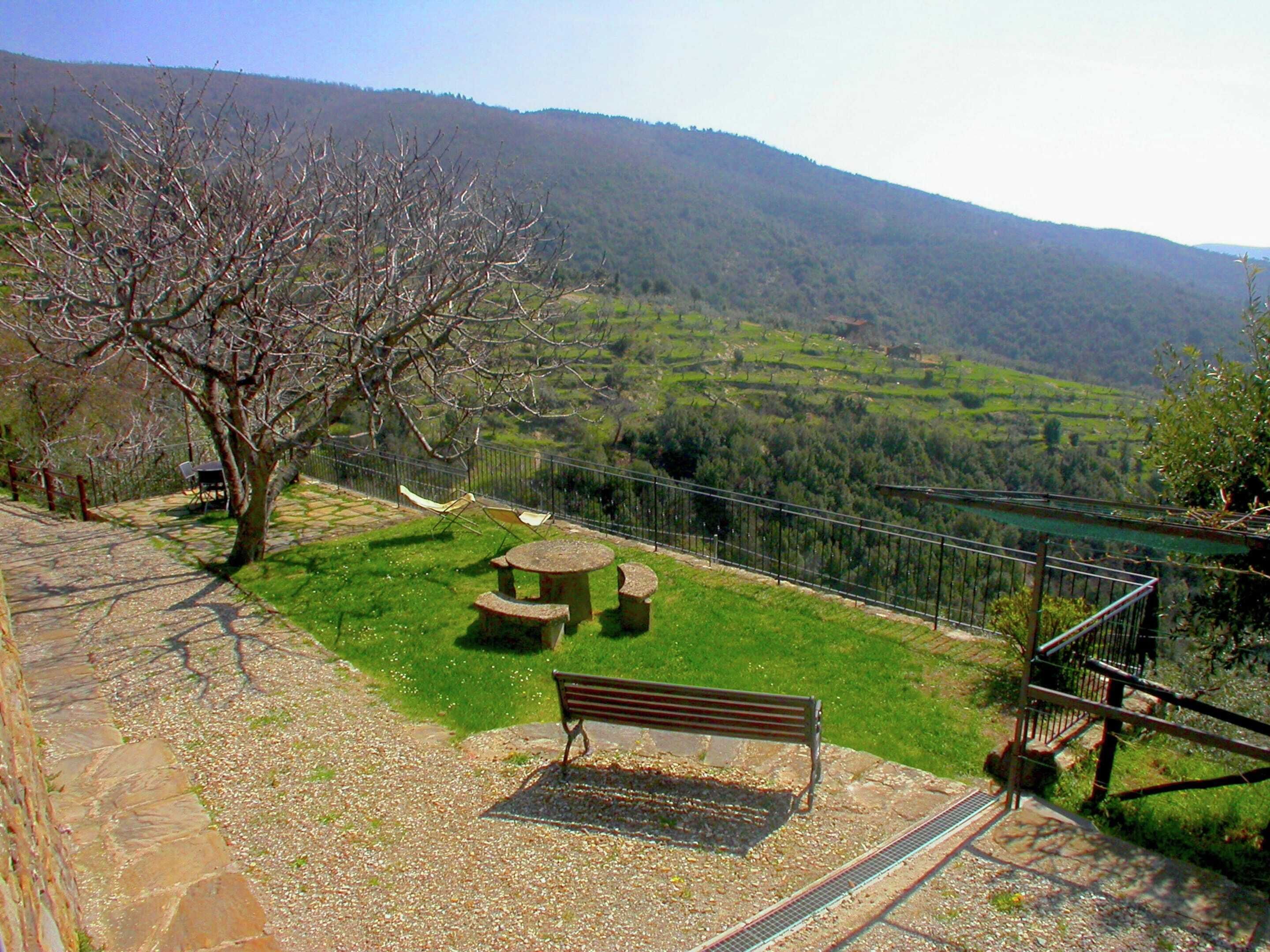 A park with a bench, picnic table, and a fenced area overlooking a valley.