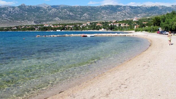 A beach with clear water, a sandy shore, and a mountainous backdrop. - Exotic Holiday Home in Tribanj-Krušćica near Sea (Starigrad)