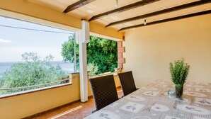 A dining area with a table set for two, a potted plant, and a view of the sea. - Exotic Holiday Home in Tribanj-Krušćica near Sea (Starigrad)