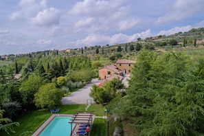A villa with a swimming pool, surrounded by lush greenery and hills.