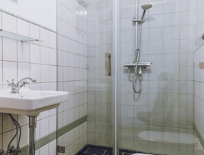 Une salle de bain avec un lavabo, une douche et des murs carrelés.