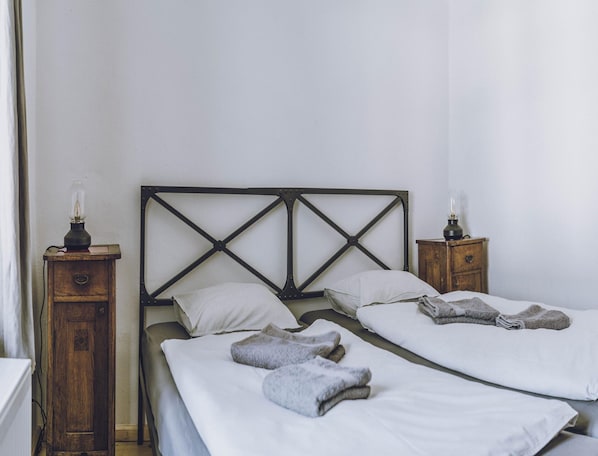 Una habitación sencilla con una cama, dos mesitas de noche y una lámpara en cada una.