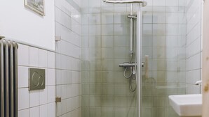 Un bany amb dutxa de vidre, vàter i rentapans.