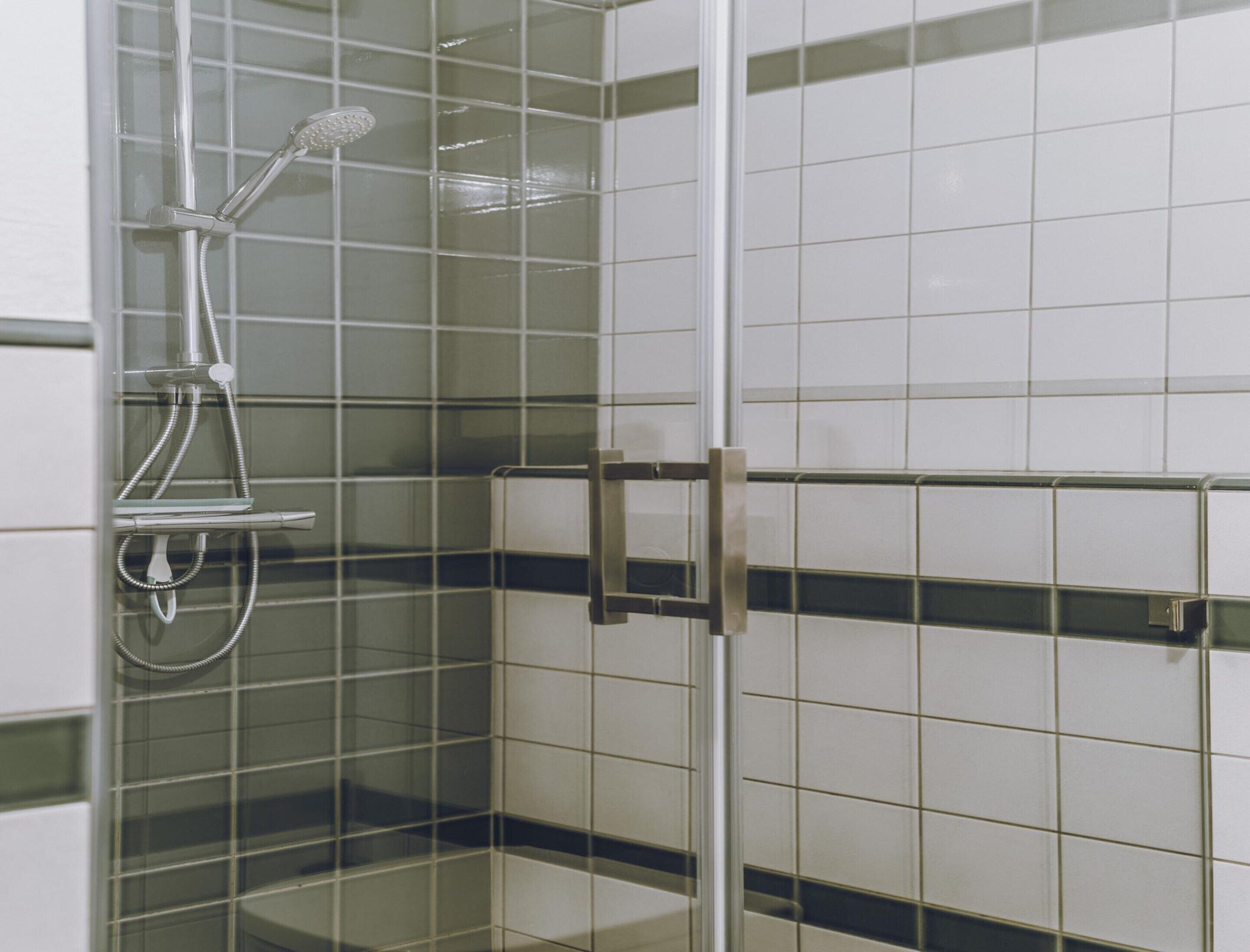 A shower with a glass door and a metal handle.