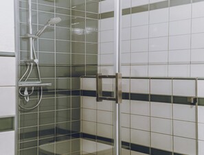 Une douche avec une porte en verre et une poignée en métal.