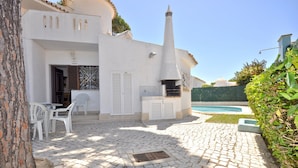 A courtyard with a stone floor, outdoor seating, a chimney, and a swimming pool. - Villa in Typical Portuguese Style, Quiet Area of Vilamoura With Private Pool (Loulé)