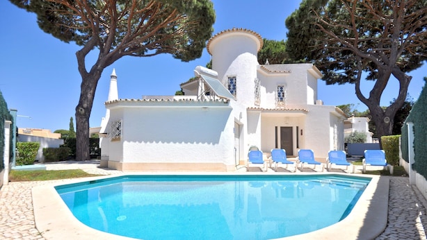 A swimming pool with lounge chairs, a white building with a dome-shaped roof, and trees in the background. - Villa in Typical Portuguese Style, Quiet Area of Vilamoura With Private Pool (Loulé)