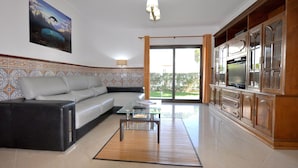 A living room with a sofa, a coffee table, and a TV on a wooden cabinet. - Villa in Typical Portuguese Style, Quiet Area of Vilamoura With Private Pool (Loulé)