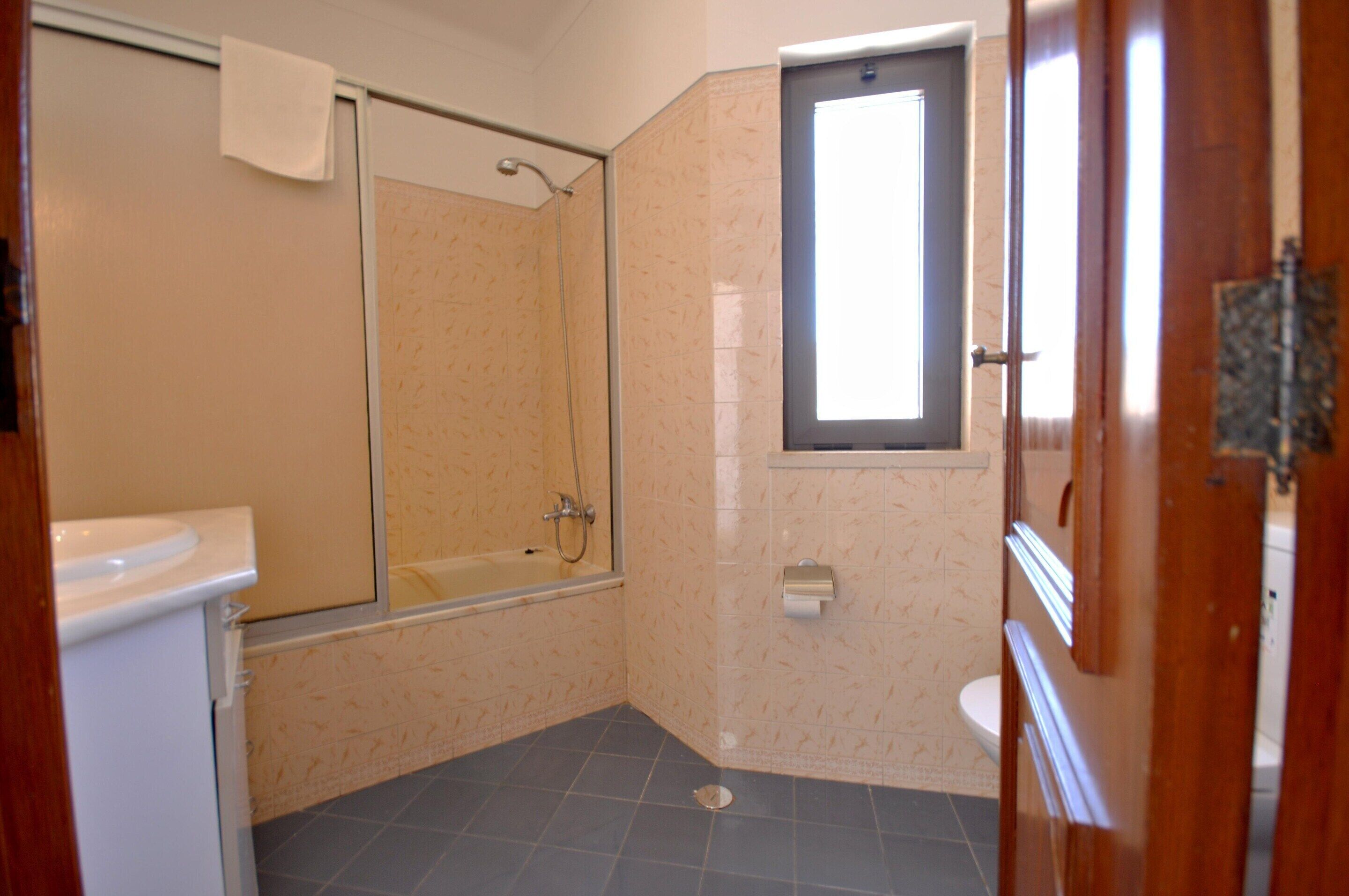 A bathroom with a shower, toilet, and sink.