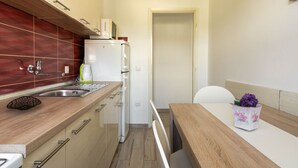 Una cucina compatta con frigorifero, lavello e zona pranzo con una sedia e un tavolo.