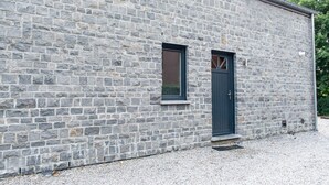 A stone building with a dark door and a small window. - Pleasant Holiday Home With Infrared Sauna (Durbuy)