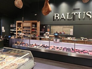 A store interior with a deli counter, refrigerated display cases, and shelves stocked with products.