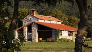 A stone building with a red roof, surrounded by trees and a grassy field. - Picturesque Mansion in Kozljak (Krsan)