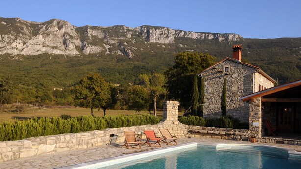 A stone building with a pool, surrounded by a stone wall and a view of mountains. - Picturesque Mansion in Kozljak (Krsan)