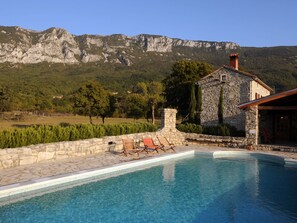 A stone building with a pool, surrounded by a stone wall and a view of mountains. - Picturesque Mansion in Kozljak (Krsan)