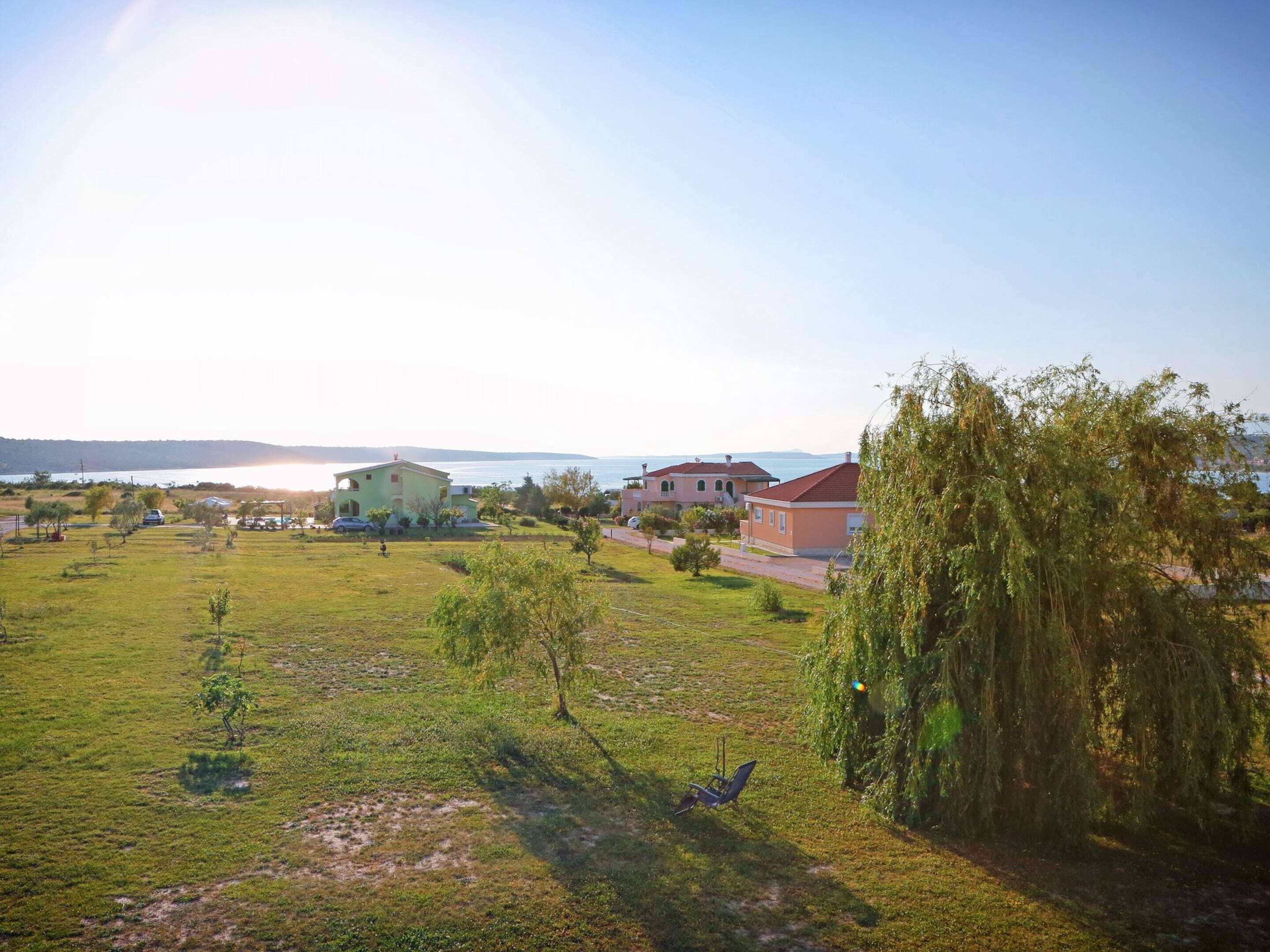 A coastal property with multiple buildings, a grassy field, and a view of the sea.