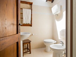 Ein Badezimmer mit Holztür, Waschbecken, Toilette und Spiegel.