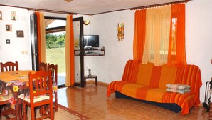 A living room with a sofa, TV, and dining area with chairs and a table.