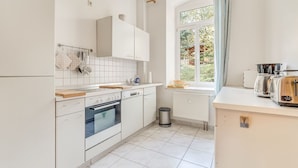 A modern kitchen with white cabinets, a built-in oven, a sink, and a window with a view of greenery outside.