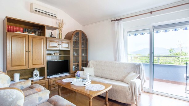 A living room with a sofa, a wooden cabinet, a television, and a balcony with a view. - Modern Apartment in Viskovo With Balcony (Viskovo)