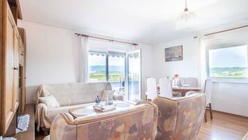 A cozy room with a sofa, chairs, a dining table, and a view of the landscape.