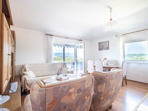 Une pièce confortable avec un canapé, des fauteuils, une table à manger et une vue sur le paysage.