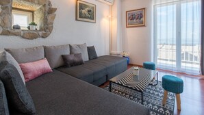 A modern living room with a grey sofa, a patterned coffee table, and a stone wall. - Holiday Home in Podstrana Near Beach (Podstrana)