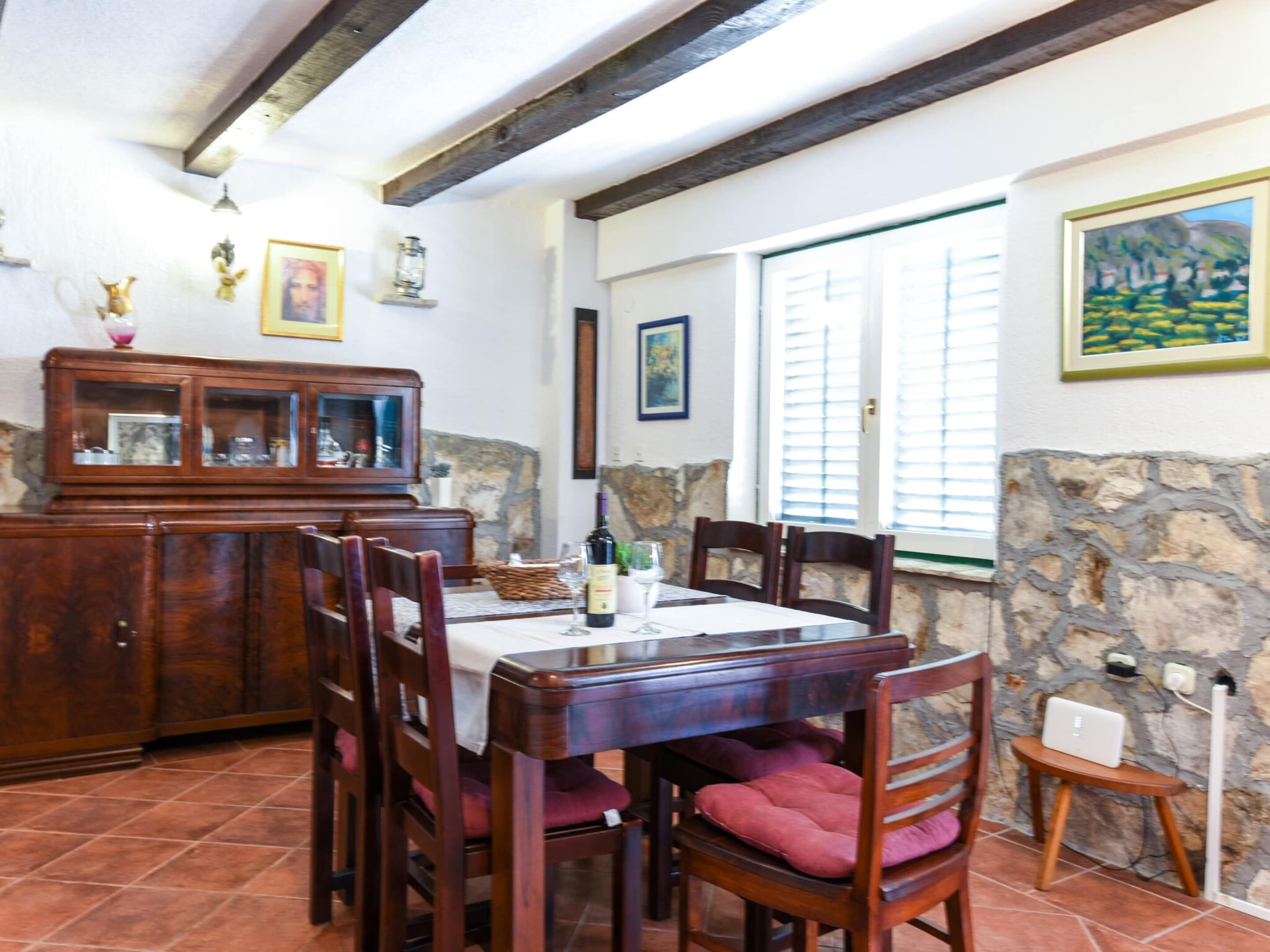 Zona pranzo con tavolo in legno, sedie e un armadietto.