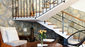A cozy living area with a stone wall, a wooden staircase, a round wooden table, and two chairs. - Holiday Home in Podstrana Near Beach (Podstrana)