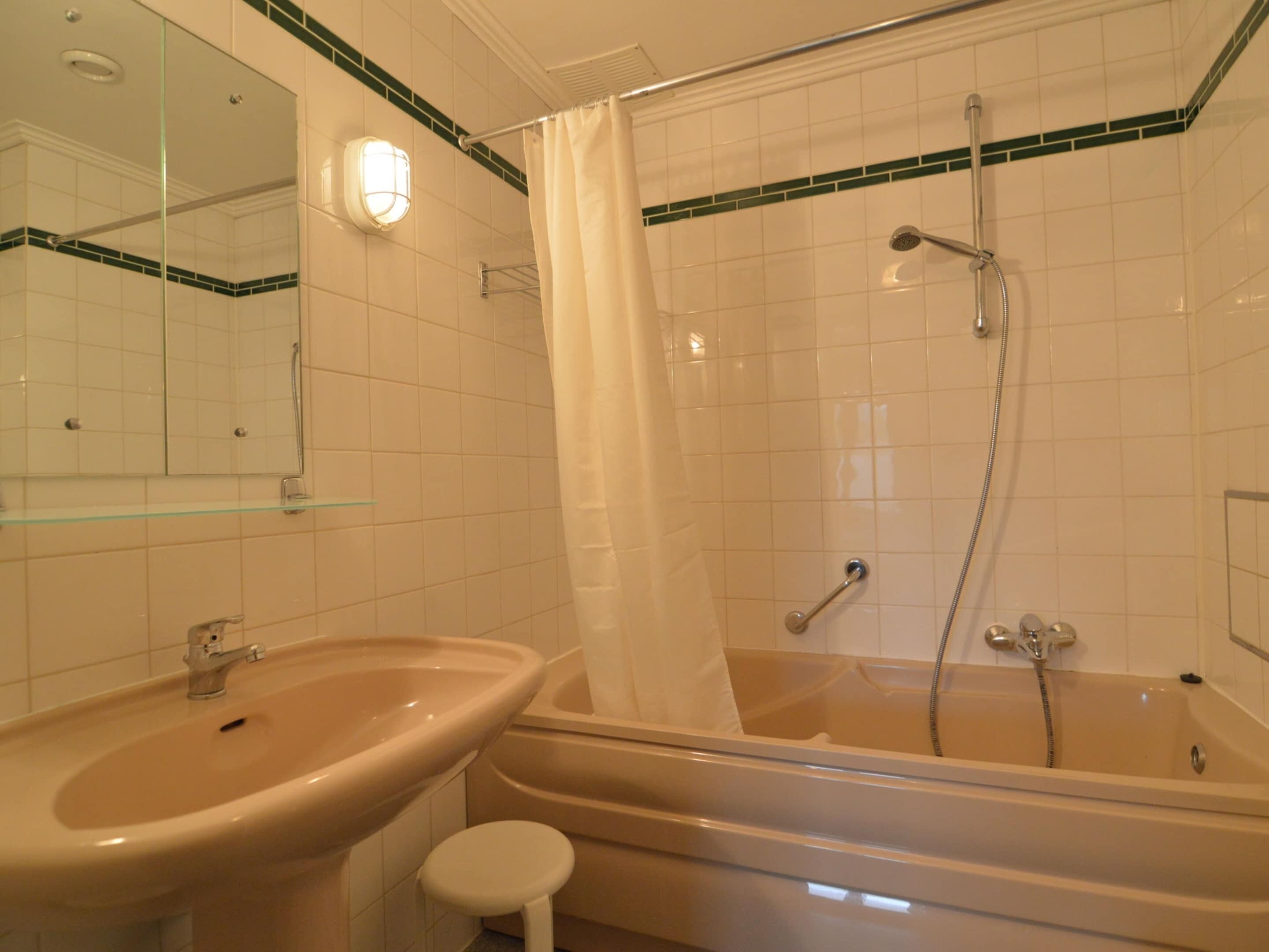 A bathroom with a sink, mirror, shower, and bathtub.