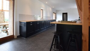 A modern kitchen with dark cabinets, a wooden countertop, and a bar area with stools. - Holiday Home in Leglise Near Ardennes River (Léglise)