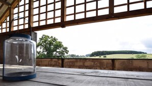 A rustic wooden table with a clear view of a rural landscape, including trees and a distant hill. - Holiday Home in Leglise Near Ardennes River (Léglise)