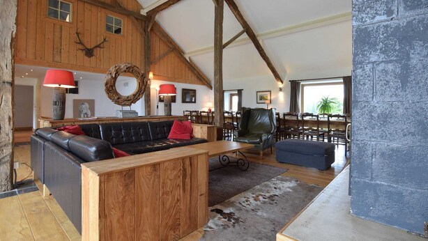 A rustic interior with a wooden ceiling, leather sofas, a fireplace, and a dining area. - Holiday Home in Leglise Near Ardennes River (Léglise)