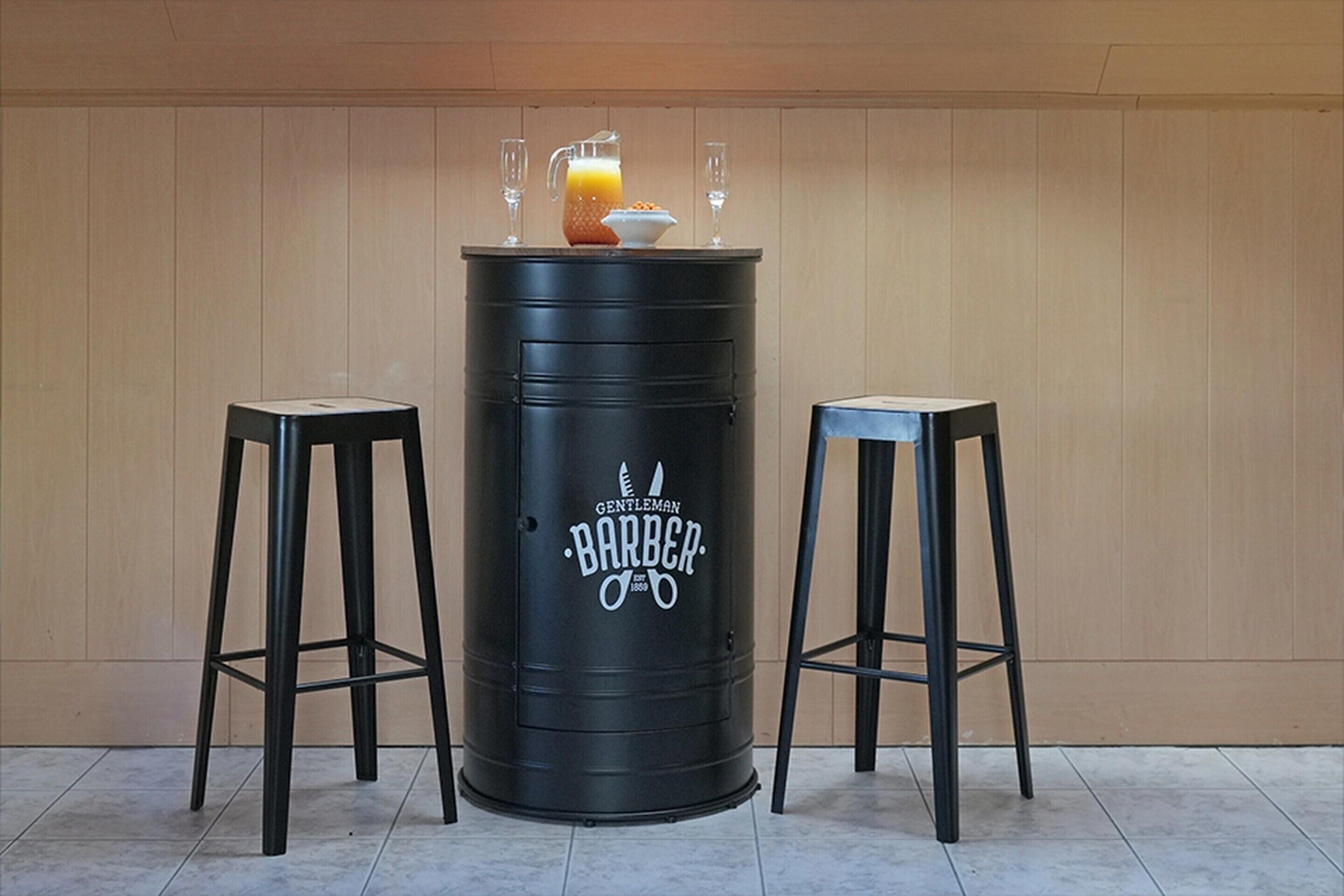 A black barrel with the words "Gentleman Barber" and a logo, flanked by two black stools.