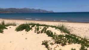 A beach with sand and sparse vegetation, a clear sky, and distant mountains. - Apartment in Alcamo Near the Beach (Alcamo)