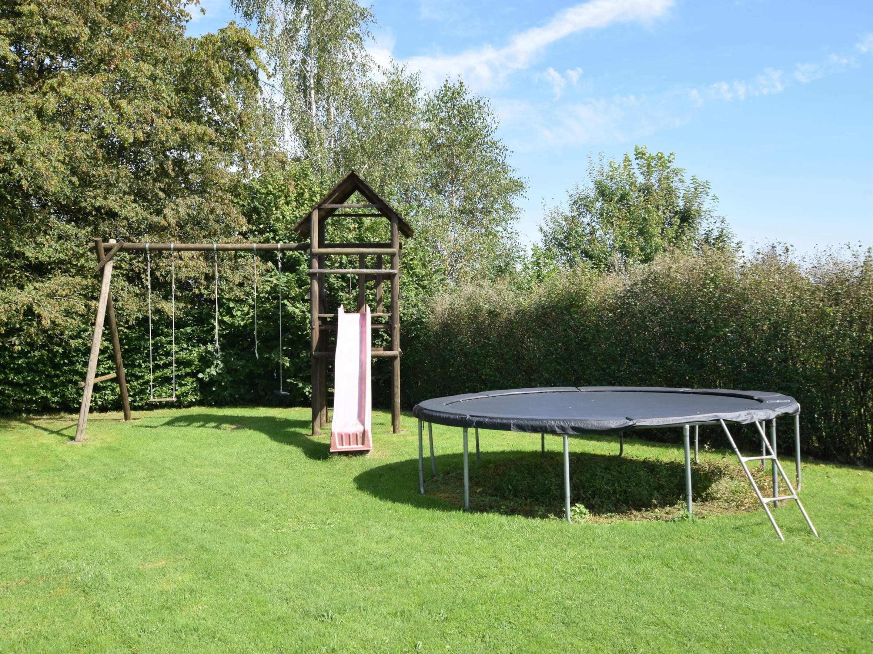 A playground with a swing set, a slide, and a trampoline.