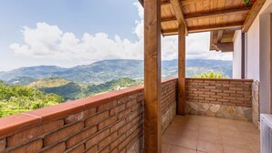 Un balcón con vistas a colinas verdes y un cielo despejado.