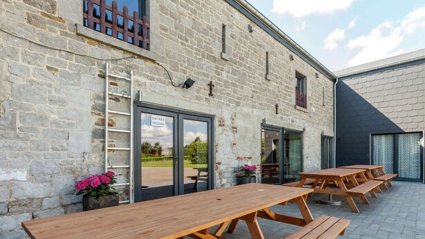A stone building with wooden picnic tables and a door labeled "ENTREE INGANG". - Ouffet Villa With Sauna, Liege (Ouffet)