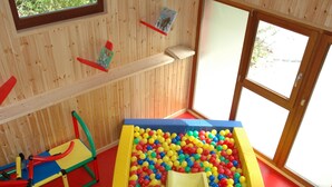 A play area with a ball pit and a slide, wooden walls, and a window. - Holiday Home in Belgium With Kids' Playroom (Somme-Leuze)