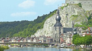 Uma cidade histórica com uma igreja e um castelo imponentes, erguidos sobre um penhasco com vista para um rio.