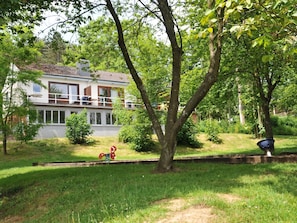 Een huis met een balkon, omringd door bomen en een gazon.