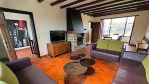 A living room with a stone fireplace, a television, and a sofa. - House in Noiseux With Bubble Bath & Garden (Somme-Leuze)