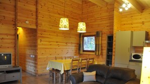 A cozy cabin interior with a dining area, a sofa, a TV, and a kitchen area. - Apartment in Belgium Near Scenic Spots (Viroinval)